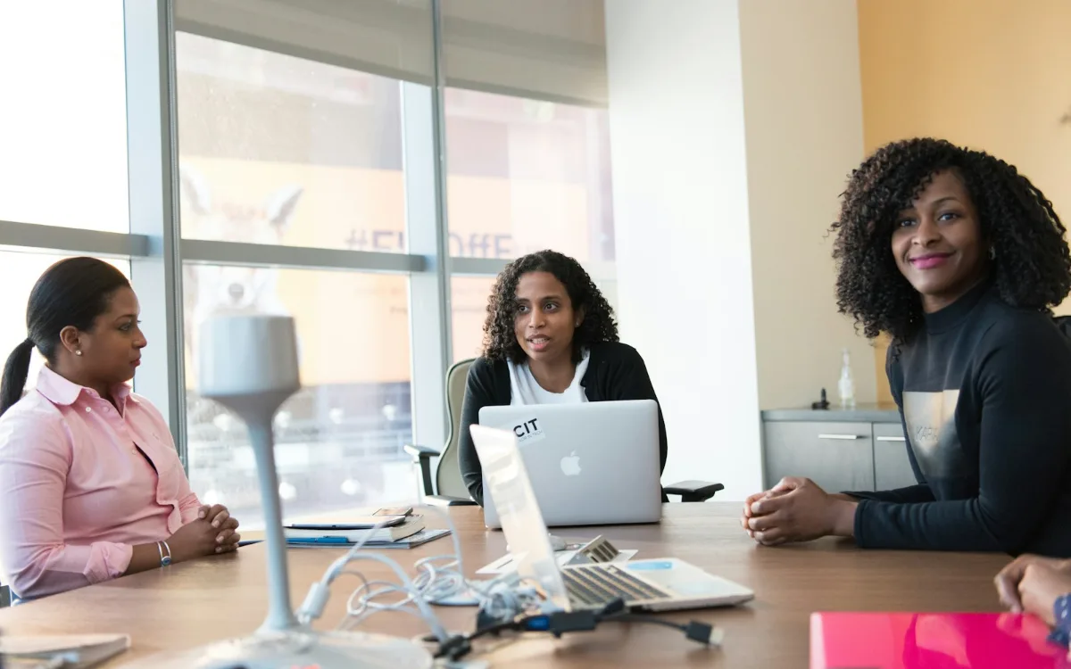 Trois collaboratrices en séance de travail dans un bureau lumineux.